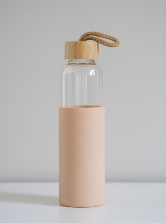 Borosilikaattilasi pullo. Pastellisen vaaleanpunainen silikonisuoja sekä bambukorkki. Vaalea tausta