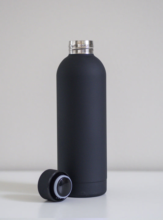Musta ruostumatonta terästä oleva juomapullo ja korkki vieressä. Valkoista taustaa vasten