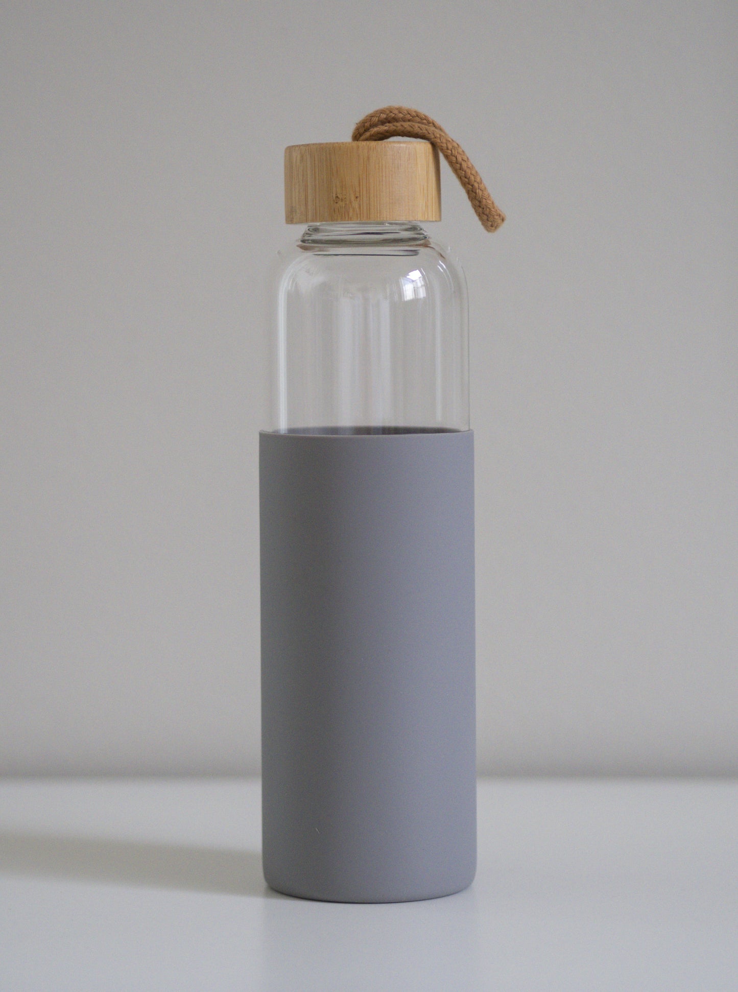 Dark gray borosilikaattilasipullo bambukorkilla pystyasennossa. Vaalea tausta