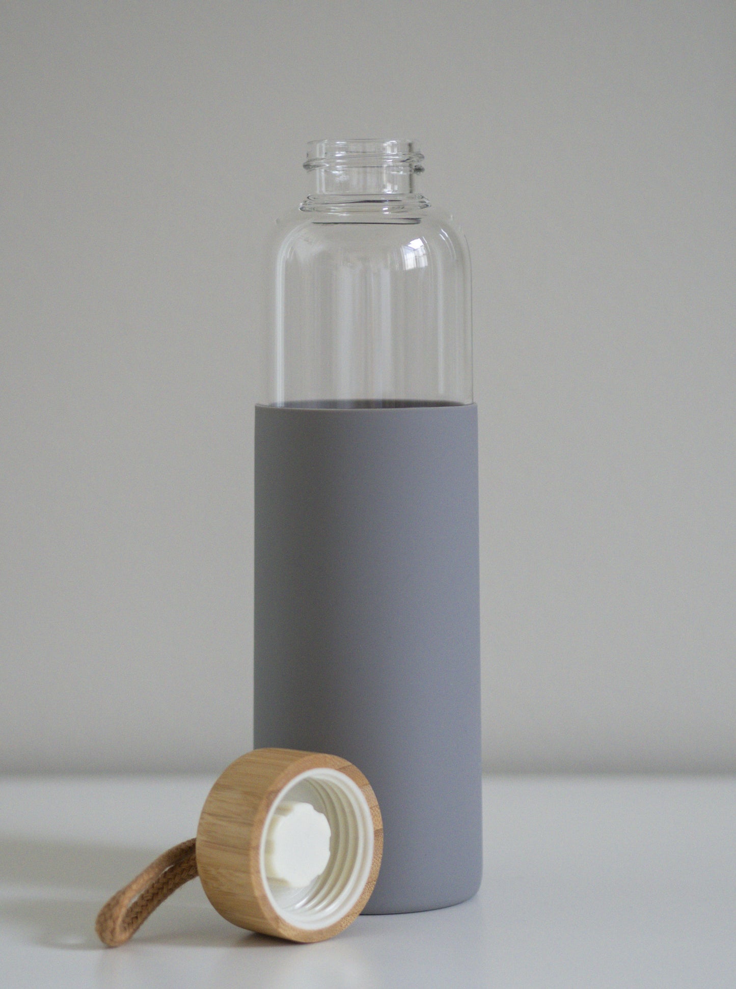 Lasipullon yksityiskohta näyttää harmaan silikonisuojan ja bambukorkin