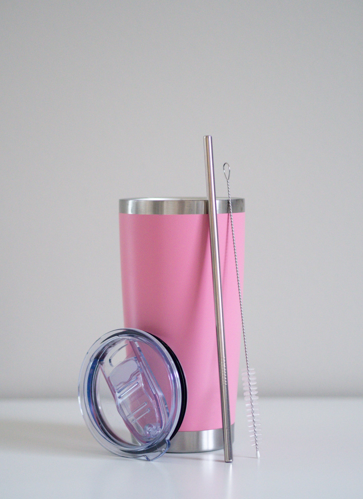 Classic Pink -terästumbleri, johon nojaa ruostumaton teräspilli, puhdistusharja ja läpinäkyvä muovikansi