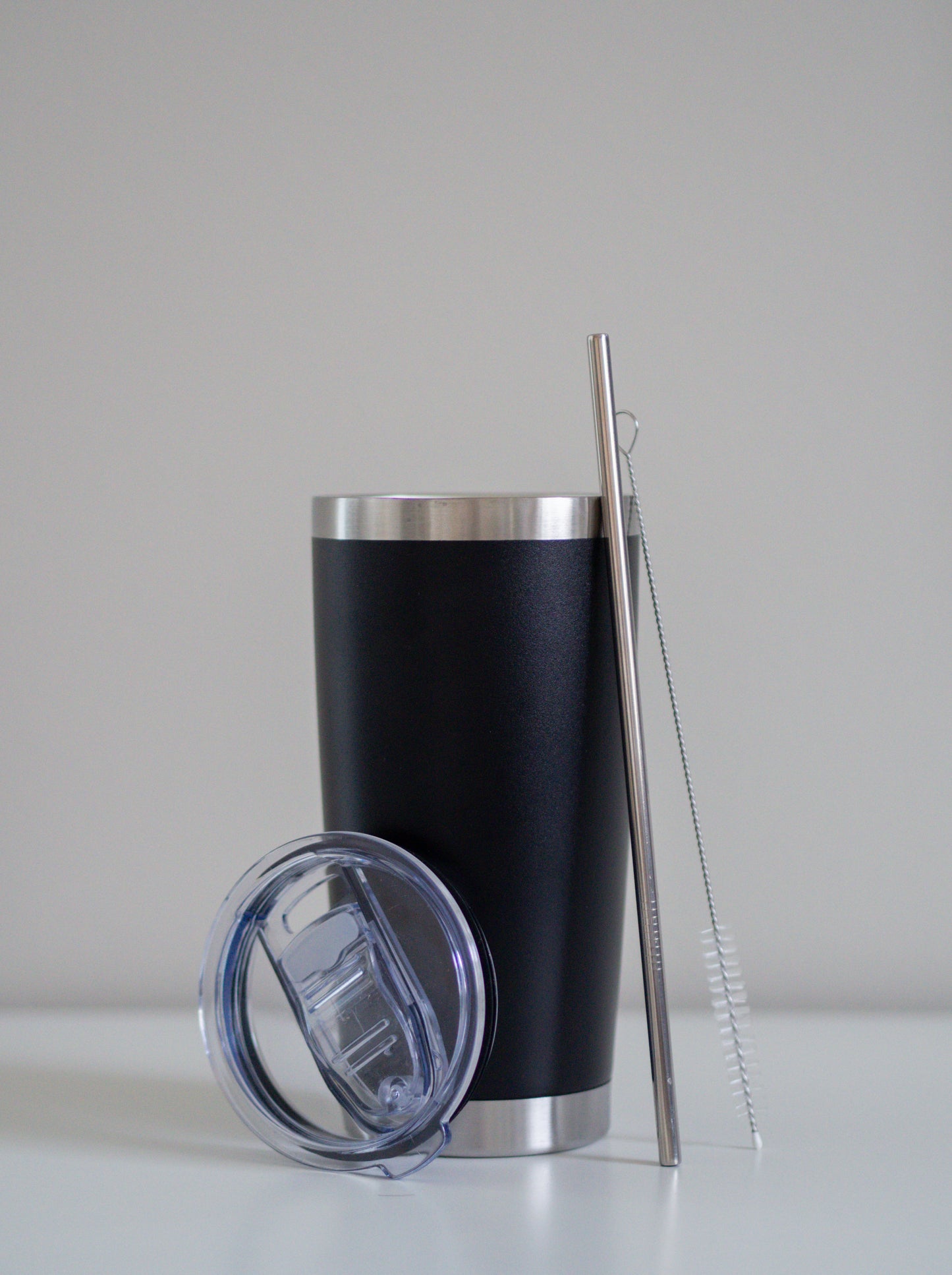 Classic Black-terästumbleri, johon nojaa ruostumaton teräspilli, puhdistusharja ja läpinäkyvä muovikansi