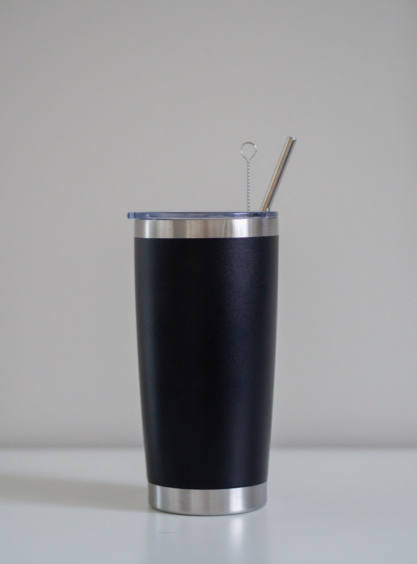 Ruostumattomasta teräksestä valmistettu musta tumbleri pillillä, pulloharjalla ja kannella