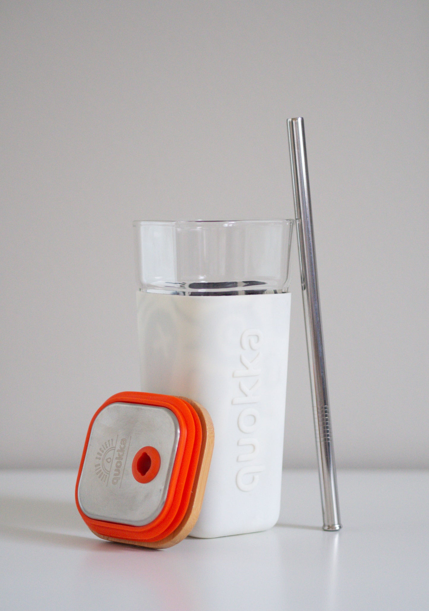 Lasinen Quokka tumbleri valkoisella silikonikauluksella, bambukannella ja ruostumattomasta teräksestä valmistetulla pillillä
